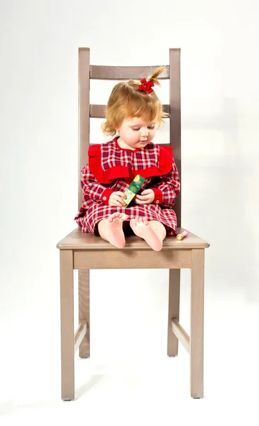 Linda niña en vestido rojo sentado en una silla — Foto de Stock