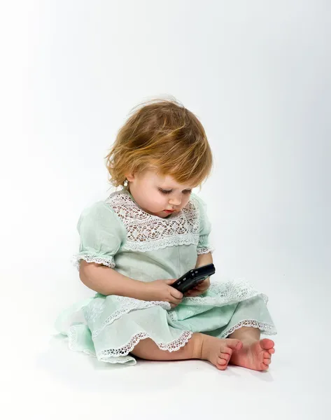 可爱的小女孩，带着白色背景的手机 — 图库照片