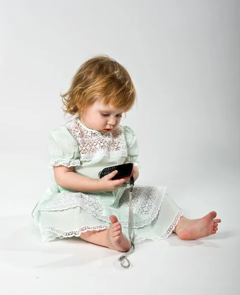 Schattig klein meisje met mobiele telefoon op witte achtergrond — Stockfoto