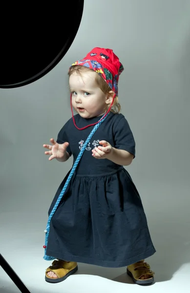 Милая маленькая девочка позирует в красной шляпе и темном платье — стоковое фото