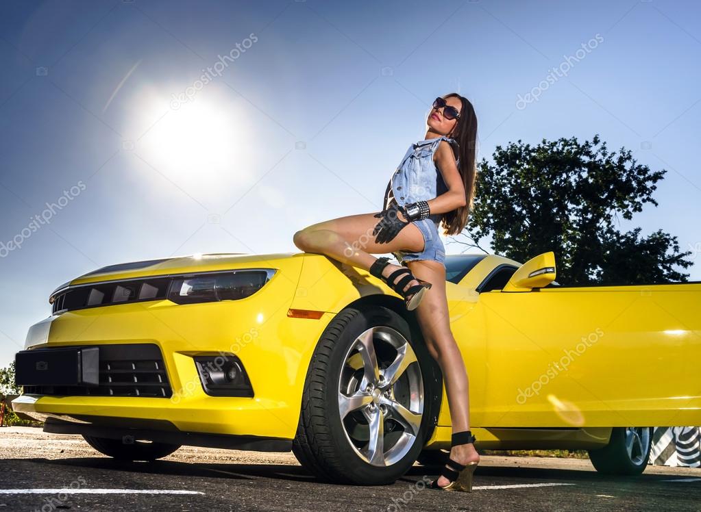 Красивая девушка позирует у спортивного автомобиля