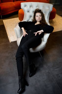 Güzel genç kız şık beyaz bir koltukta poz veriyor..