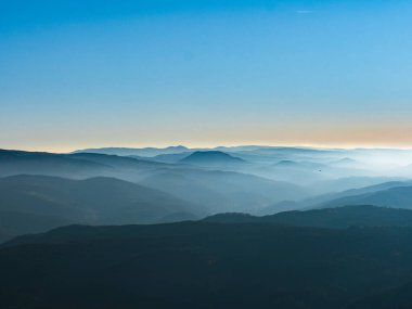 İlk kış soğuğu. Vosges dağlarının tepelerinde ağaçlar kırağı ile kaplıdır. Beyaz kar ve mavi gökyüzü. Dağların siluetlerinin panoramik görüntüsü.