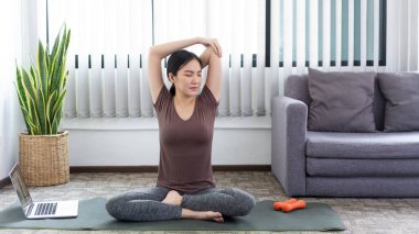 Huzurlu bir oturma odasında yoga yapmak için konsantre olan sakin bir kadın..