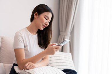 Oturma odası konsepti. Uzun saçlı bir kız, rahat odasındaki elektronik aletlerle vakit geçiriyor..