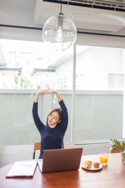 Ev konseptiyle çalışan bir bayan girişimci evinde uzaktan çalışırken kollarını açıp rahatlıyor..