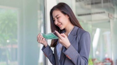 Çalışan kadın konsepti. Kendini Corona virüsünden korumak için tek kullanımlık maske takarak müşteriyle buluşmadan önce kendini hazırlayan bir çalışan kadın..