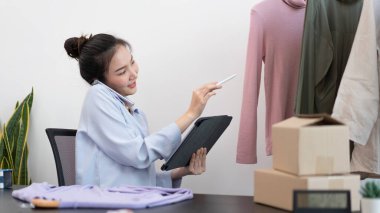 Canlı alışveriş kavramı. Bir kadın satıcı günün siparişlerini kontrol etmek için tablet kalem kullanıyor..