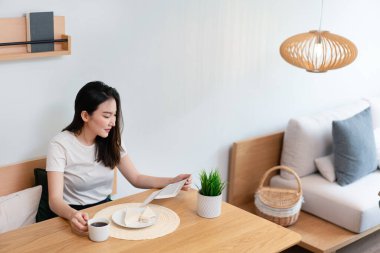 Oturma odası konsepti. Güzel bir bayan gazetede makaleyi okurken bir diğeri de sabahları elinde bir fincan kafein içeceği tutuyor..