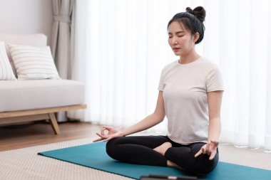 Üretken aktivite kavramı sakin bir kızın oturma odasındaki huzurlu atmosferde tek başına meditasyon yapmaya odaklanması..