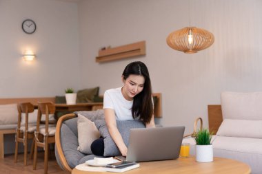 Kahve dükkanındaki oturma odası konsepti. Laptopunu kullanan bir kız. Elinde bir bardak portakal suyuyla internete giriyor..