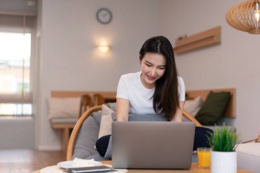 Kahve dükkanındaki oturma odası konsepti. Laptopunu kullanan bir kız. Elinde bir bardak portakal suyuyla internete giriyor..