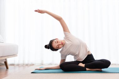 Üretken aktivite kavramı beyaz tişört giyen genç bir kadın pilates yaparak vücudunun esnekliğini deniyor..