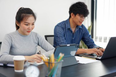 Ofis işi konsepti. İki iş adamı ofiste iki fincan kahveyle cihazlar üzerinde çalışıyor..