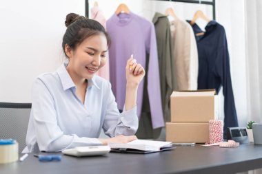 Canlı alışveriş kavramı. Bir kadın satıcı posta yoluyla müşterilere göndermeden önce hisse senetlerini sayıyor ve birkaç paketi kontrol ediyor..