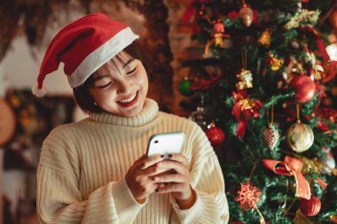 Kız akıllı telefon kullanır ve Noel tatilinin tadını çıkarır, yeni yıl kutlama konsepti.