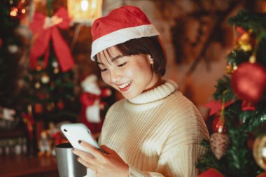 Kız akıllı telefon kullanır ve Noel tatilinin tadını çıkarır, yeni yıl kutlama konsepti.