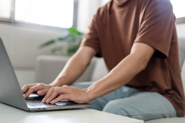 Teknoloji kavramı. Kahverengi tişörtlü adam bilgisayarında bir şeyler yazmaya odaklanıyor..