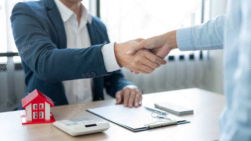 The real estate concept the house estate and his client shaking hands for accepting to make the land sale contract.