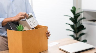 İstifa. Masanın başında duran açık mavi gömlekli adam hesap makinesini ve diğer şeyleri kutuya koyuyor..