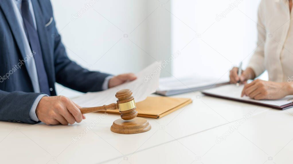 law concept the legal representative in deep blue suit gavel to approve agreement in the official document that the company submits to him while his aider sitting at the same desk with him.