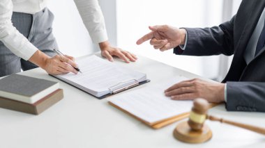Hukuk konsepti. Avukat yardımcısı elinde bir kalem tutuyor ve patronuna kafasının karıştığı terimi okuyor..