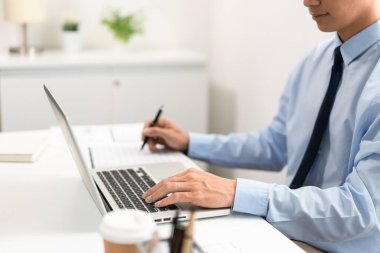 Çalışan Adam Conept ofiste oturan erkek subay sol elini dizüstü bilgisayara koydu ve sağ eliyle kağıda bir şeyler yazdı..