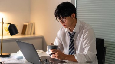 Fazla mesai. Geç saatlere kadar çalışıp, işine odaklanırken bir fincan kahve içen bir ofis çalışanı..