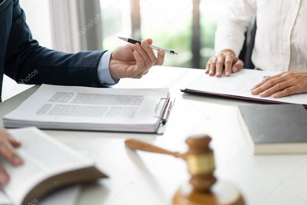 law concept The solicitor, the man in blue suit, giving his pen to his aider for having her sign on the official document.