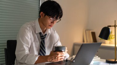 Fazla mesai. Geç saatlere kadar çalışıp, işine odaklanırken bir fincan kahve içen bir ofis çalışanı..