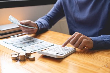 Tasarruf kavramı. Koyu mavi kazaklı adam aylardır biriktirdiği para ve paraları saymaya çalışıyor..