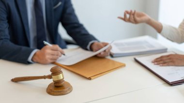 Hukuk danışmanı, kanun güçlendiricisinin raporunu dinleyip anlaşma kağıdını yazarak düzeltiyor..