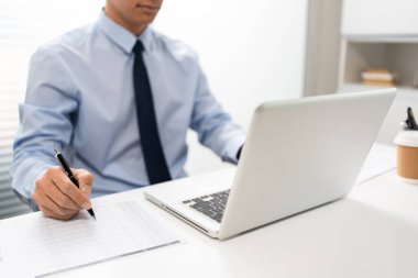 Çalışan Adam Conept ofiste oturan erkek subay sol elini dizüstü bilgisayara koydu ve sağ eliyle kağıda bir şeyler yazdı..