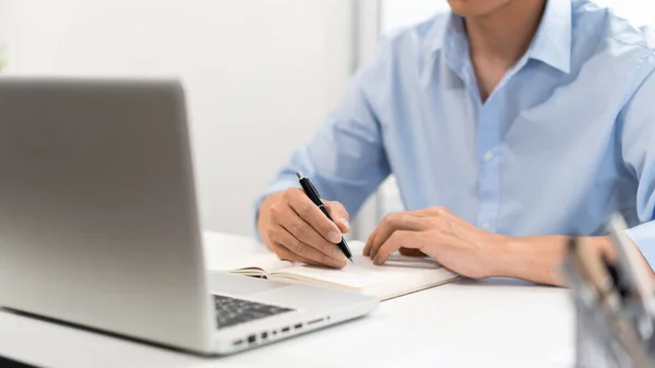 仕事中の男のコンセプトノートパソコンに集中して机に座って紙に何か書いてる男 — ストック写真