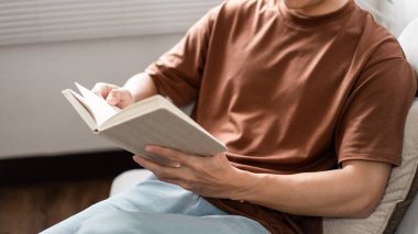 Teknoloji kavramı. Dizüstü bilgisayara odaklanırken sırtı koyu sarıya yaslanan gözlük takan adam..