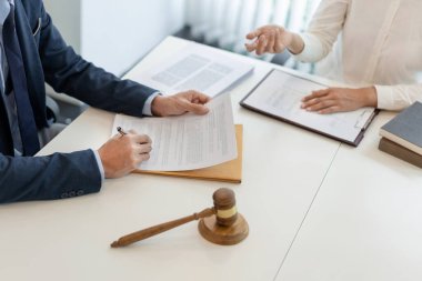 Hukuk danışmanı, kanun güçlendiricisinin raporunu dinleyip anlaşma kağıdını yazarak düzeltiyor..