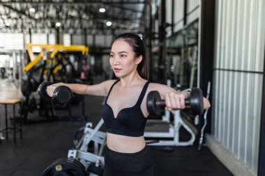 Egzersiz başlatıcısı iki kolla da dengeleme yaparak dambıl üzerinde çalışmaya odaklanır..