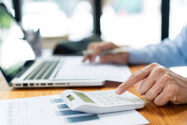 Концепция бизнес-аналитика: бухгалтер-мужчина концентрируется на деталях продажи, нажимая на калькулятор.