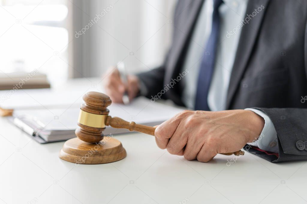 law concept the lawyer in dark bule suit signing his signature on the official document and gaveling for approving the term of it.