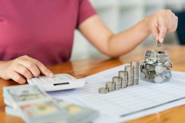 Tasarruf konsepti. Kadın para biriktirir ve hesap makinesini kullanarak parayı sayar..