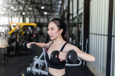 Egzersiz başlatıcısı iki kolla da dengeleme yaparak dambıl üzerinde çalışmaya odaklanır..