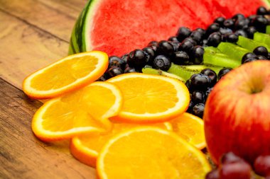 Taze meyve konsepti, ahşap arka planda renkli karpuz kivi portakalı ve yabanmersini meyveleri..