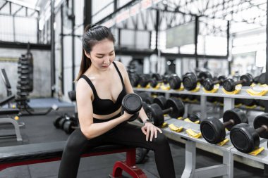 Egzersiz konsepti. Spor yapan kadın halterin sağ elinde bir dambıl taşımaya dikkat ediyor..