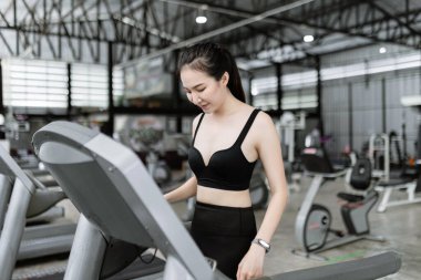 Egzersiz konsepti. Kadın koşucu ayakta ve koşu bandına mutlu ve gülen yüzle başlamak üzere..