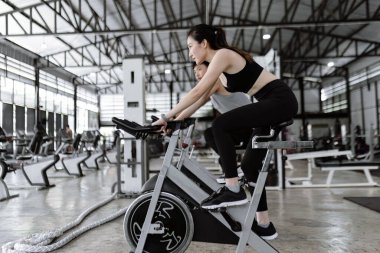 Egzersiz konsepti. İyi görünümlü bayan ve kaslı adam spor bisikletleri sürerken sohbet ederken eğleniyorlar..