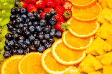 Taze meyve kavramı, portakallı kivi düzenlemesi ve arka plan olarak çeşitli meyveler..