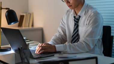 Fazla mesai. Masasında oturan ve bilgisayarını kullanarak çalışmaya odaklanan adam..