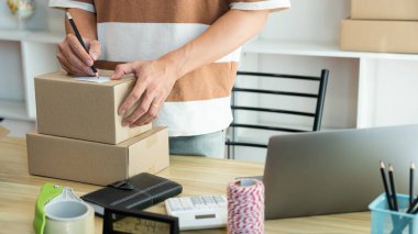 Çevrimiçi alışveriş kavramı. Satıcı paketin üzerine müşteri adresini yazıyor ve göndermeye hazır..