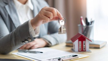 Sigorta konsepti. Emlak temsilcisi kontratı imzaladıktan sonra ev anahtarını müşterisine veriyor..