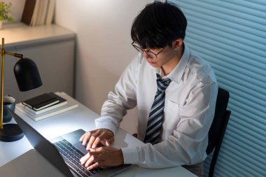 Fazla mesai. Ofis personeli masasında oturmuş, evrak okuyor ve not defterine yazı yazıyor.